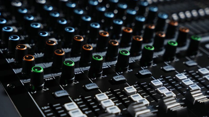 Detailed view of an audio mixing console with colorful lights in a professional studio setting.