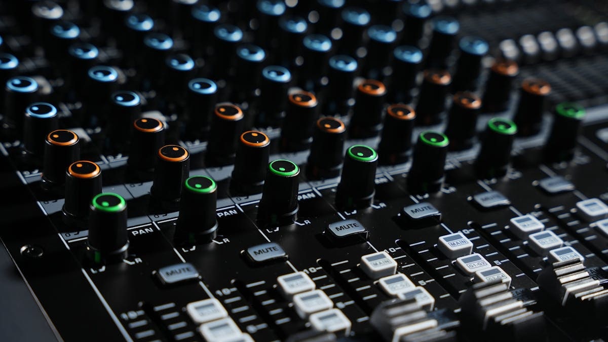 Detailed view of an audio mixing console with colorful lights in a professional studio setting.